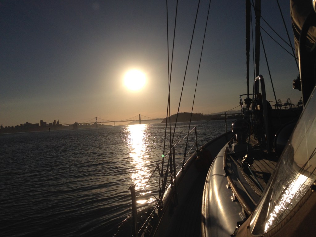 view from onboard sailboat heading toward setting sun